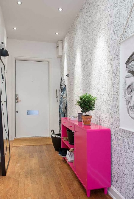 Różowa komoda nowoczesna,tapeta w czarno-białe drobne wzorki,lusro podłogowe w czarnych ramach,nowoczesne grafiki na ścianie