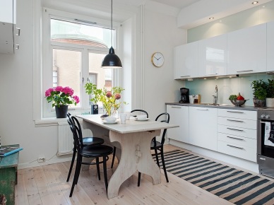 Biała minimalistyczna kuchnia skandynawska z rustykalnym stołem,czarnymi krzeslami z giętego drewna, i dywanem w biało-czarne paski (25933)