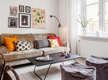 Kolorowe i graficzne poduszki ozdobne na aksamitnej beżowej sofie,czarny metalowy stolik kawowy,płócienne pufy w salonie (48100)