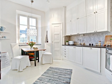 Aranżacja rozbielonego mieszkania w eleganckim stylu francuskim z kominkiem w salonie
