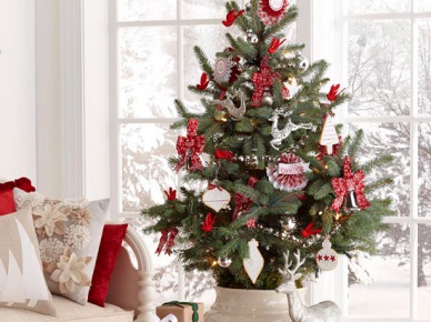 Biało-czerwone dekoracje świąteczne i mała choinka w ceramicznym wazonie na stole (27181)