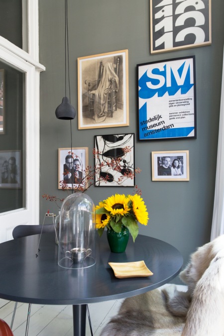 Szara ściana ,czarne wiszące lampy w nowoczesnym stylu,nowoczesne grafiki i fotogeafie retro na szarej ścianie,czarny okragły stolik