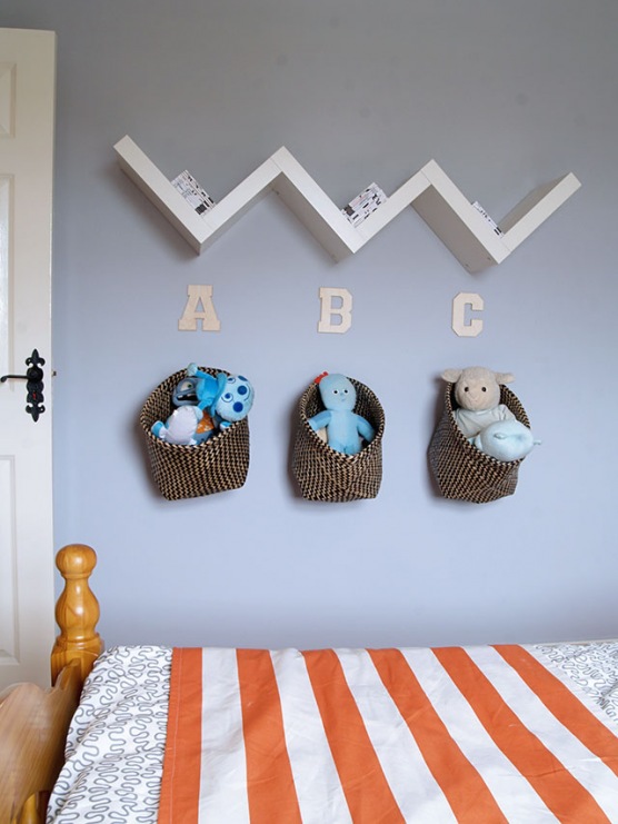 Ścienna dekoracja w pokoju dziecięcym bazuje na trzech elementach - półce w kształcie zygzaka, typografii oraz koszach...