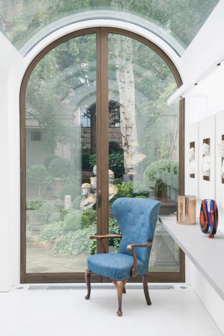 Przeszklony sufit i drzwi w stylowych łukach z widokiem na klasyczny zielony ogród angielski