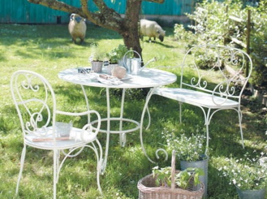 Białe kute meble ogrodowe w deserowej aranżacji w letnim ogrodzie (23932)