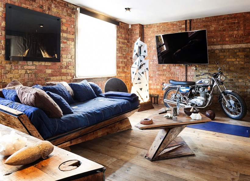 Motocykl Harley,dizajnerski stolik kawowy z drewna,oryginalana sofa z bszafirowymi poduchami i ściany z czerwonej cegły