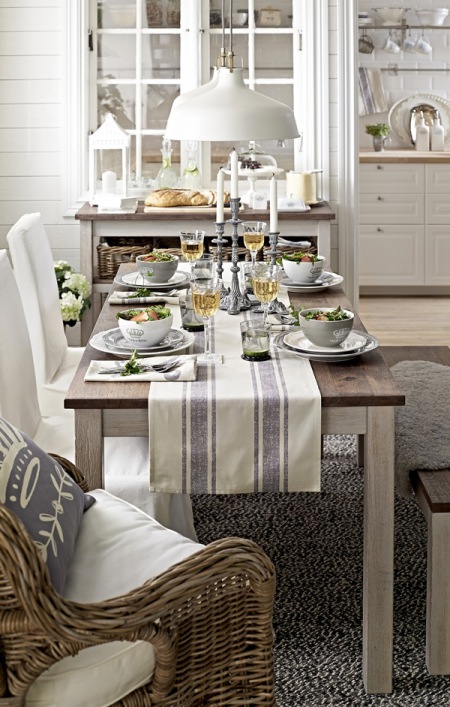 Biale lampy wiszące w stylu skandynawskim nad drewnianym stołem w jadalni z witryną