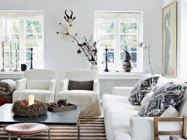 Białe sofy w salonie,drewniane fotele,biało-brązowy dywan w pasy i małe stoliki kawowe i monochromatyczne kolory poduszek dekoracyjnych (27413)