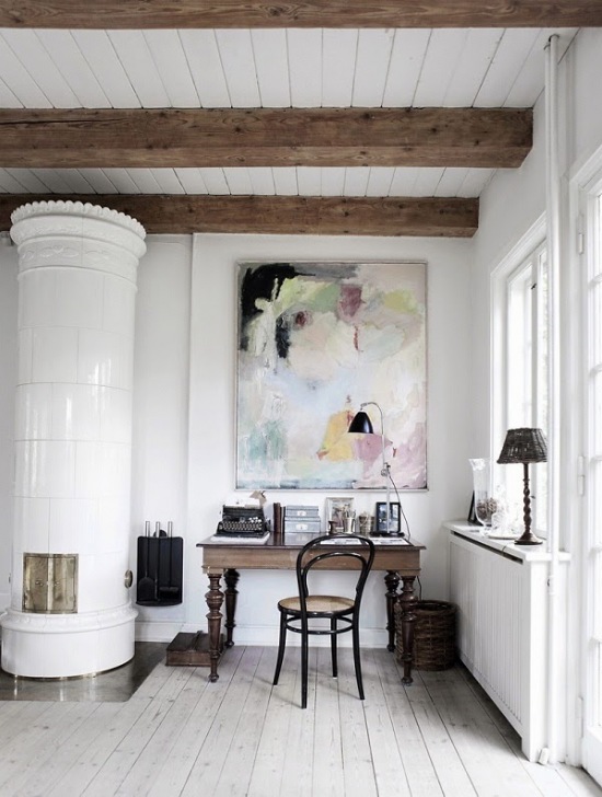 Drewniane belki,nowoczesny obraz,stylowe biurko i biały piec skandynawski