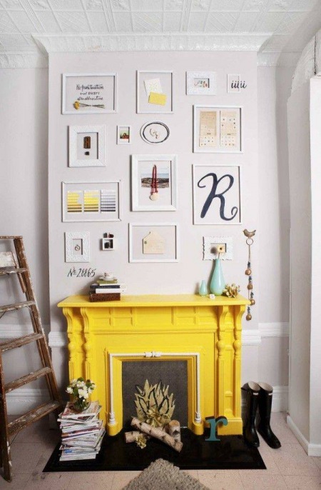 Żółta obudowa kominka z galerią obrazów na ścianie