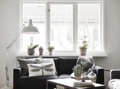 Biała lampa podłogowa,czarna sofa,graficzne poduszki z ważką i stolik pomocniczy w salonie (28351)