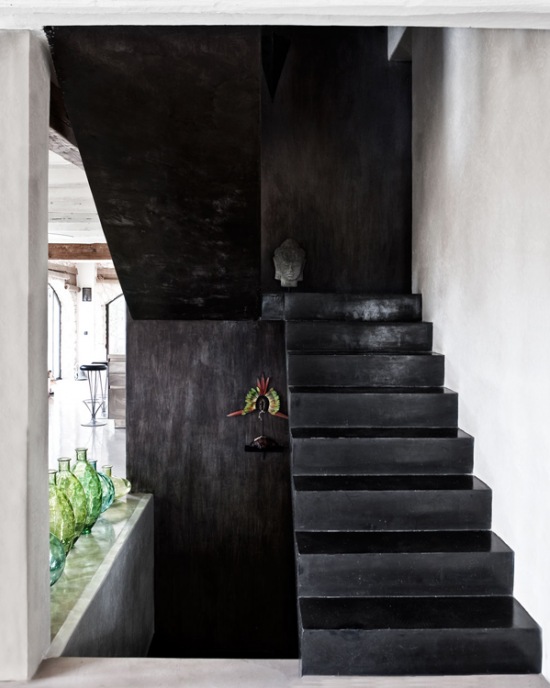 Czarne betonowe schody i szklane zielone i turkusowe butle w aranżacji domu