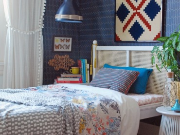 Małą sypialnię urządzono w zdecydowanych kolorach granatu, czerwieni i innych. Biała rama łóżka rozświetla nieco całość. Wnętrze wygląda bardzo przytulnie dzięki zastosowaniu wielu elementów...