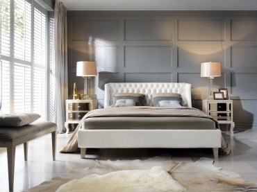 Sypialnię urządzono w eleganckich zgaszonych kolorach. Wystrój wzbogaca ciekawa ściana, a dywan dodaje przytulności.