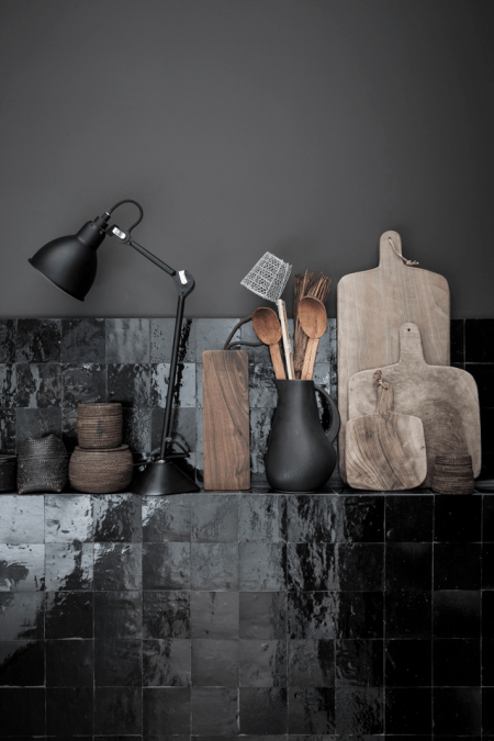 Czarne ściany i płytki w aranzacji kuchni z drewnianymi i ceramicznymi dodatkami