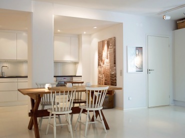 piękny i minimalistyczny przykład połączenia kilku pomieszczeń na jednej przestrzeni - to skandynawski salon razem z kuchnią i jadalnią. Mamy nieskazitelną biel, surowe palety z drewna, proste formy drewnianych mebli i nieodparty urok...