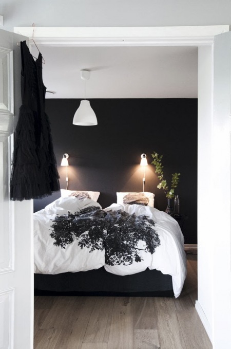 Czarna ściana i drewniana podłoga w skandynawskiej sypialni