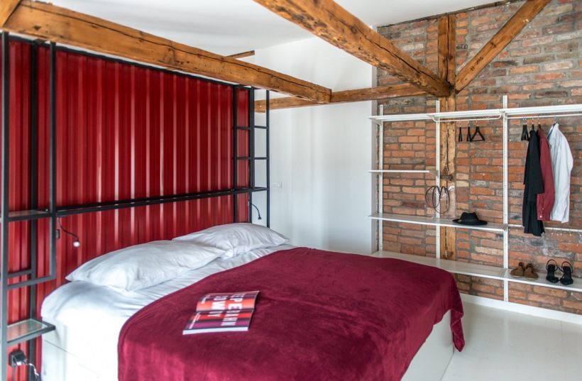 Czerwone cegły w sypialni z drewnianymi belkami na suficie