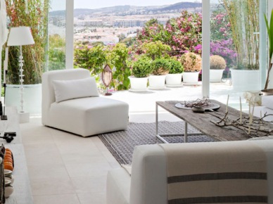 Białe sofy i fotele, biała lampa podłogowa,szary dywan w salonie z przeszkloną ścianą (23483)