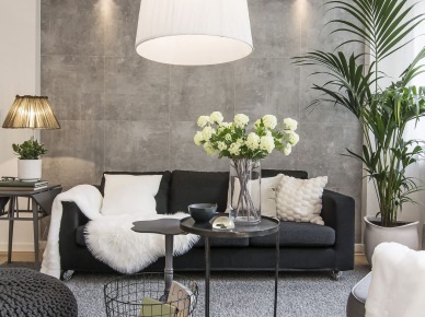 Szary salon - grafitowa sofa,szara dziergana pufa,okragły stolik z metalu i szary dywan na podłodze (24625)