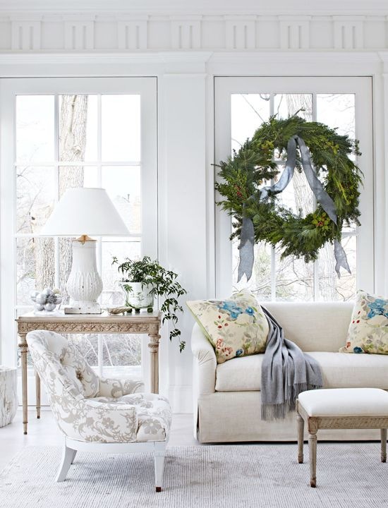 Duży wianek świąteczny w oknie białego salonu w eleganckim saloniku francuskim z konsolką i biała ceramiczna lampą stołową