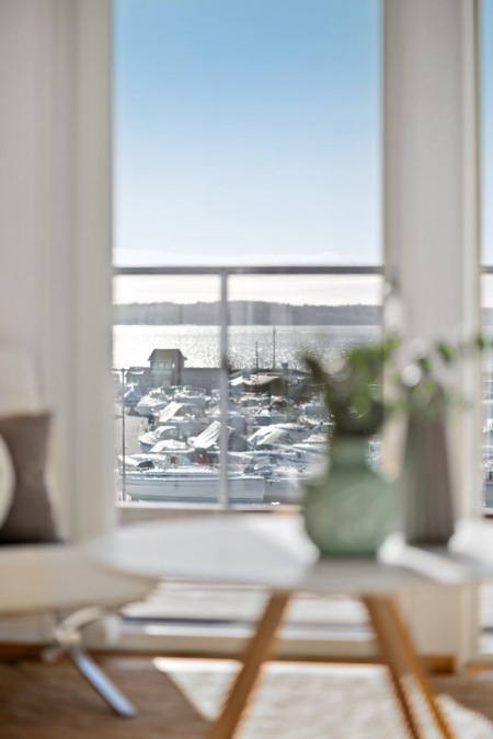Okrągły skandynawski stolik przy oknie z widokiem na fiordy