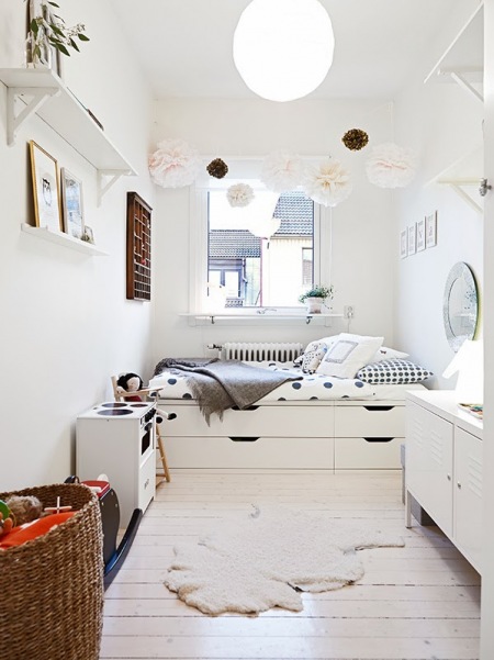 Papierowe pompony ,białe łóżko z pojemnikiem,owcza skóra in biala podłoga z desek w dziecięcym pokoju