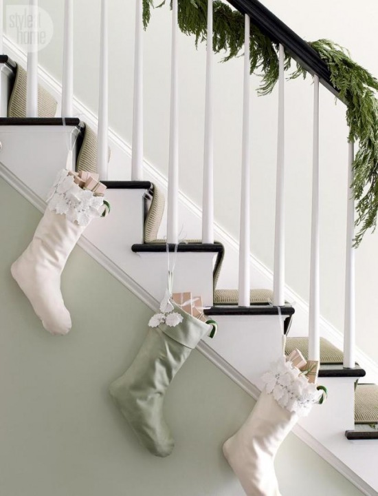 Białe schody z czarnymi stopnicami w świątecznej dekoracji z igliwia i biało-miętowych bożonarodzeniowych skarpet