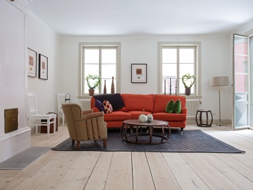 Zdjęcie salonu w stylu skandynawskim z fajną czerwoną sofa, która dodaje kontrastu.