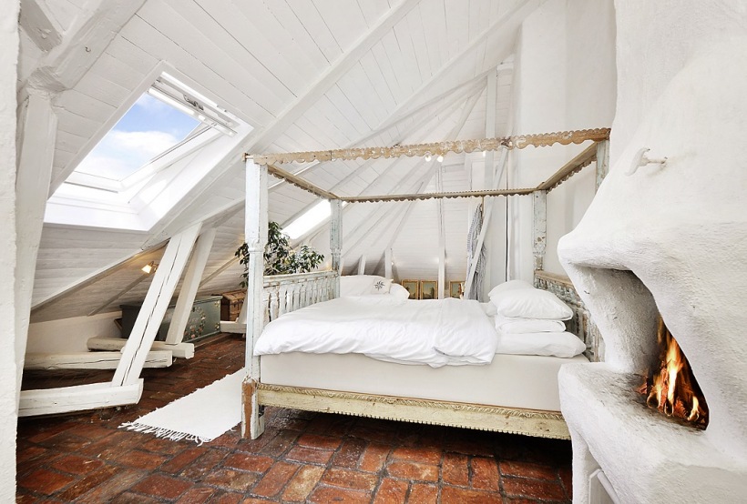 Czerwona terakota,bielone belki i łóżko w drewnianej ramie w białej sypialni na poddaszu