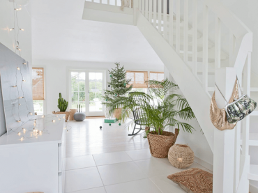 Uroczy domek w stylu skandynawskim spowity bielą od podłogi po sufit. Zielone i drewniane detale w świątecznej...
