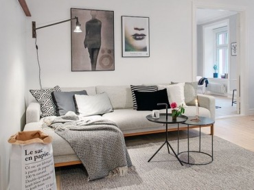 Proste, choć jednocześnie dość oryginalne w formie meble w salonie idealnie wpisują się w skandynawski styl mieszkania. Czarne dodatki w wyraźny sposób przełamują spokojny charakter wnętrza i dekorują jednocześnie...