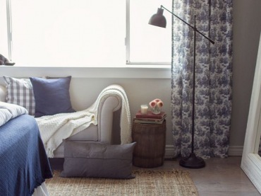 Beżowy tkany dywan w sypialni fajnie nawiązuje do drewnianych ścian. Duże białe lustro oparte o ścianę optycznie...