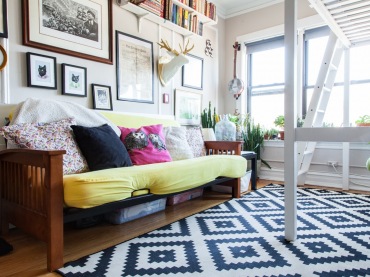 Na ścianie w salonie panuje radosny miszmasz, sofę zdobią kolorowe poduszki, a jako dodatkową ozdobę postanowiono zastosować wzorzysty dywan. Dzięki wielości takich elementów aranżacja jest naprawdę...