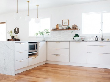 Białe szafki i białe ściany tworzą spokojne i wdzięczne tło dla dodatków, które tworzą charakter kuchni. Drewniana...