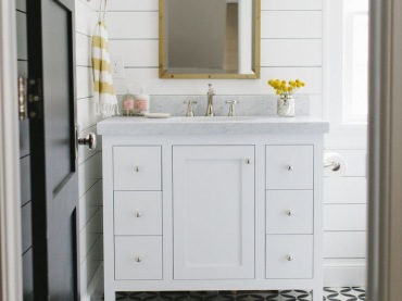 Drobny wzór na podłodze łazienki urozmaica i tak dość ciekawą przestrzeń. Biała szafka i drewniane deski na ścianie tworzą razem ładne stonowane tło, eksponując drobne detale w żółtym kolorze. Dzięki nim klasyczny zestaw bieli-szarości zyskuje na radosnym, nieco beztroskim...