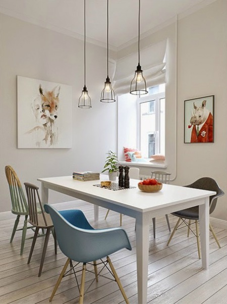 Skandynawskie plakaty na ścianie w jadalni,druciane lampy nad białym stołem z różnymi krzesłami