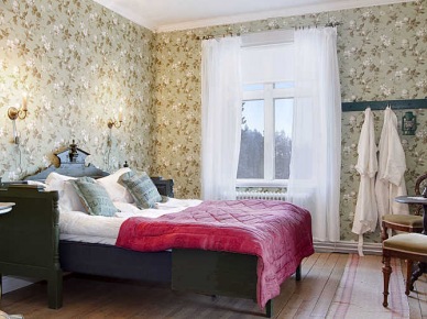 Tapeta w kwiaty,stylowe drewniane łóżko i białe firanki w eklektycznej sypialni (27640)