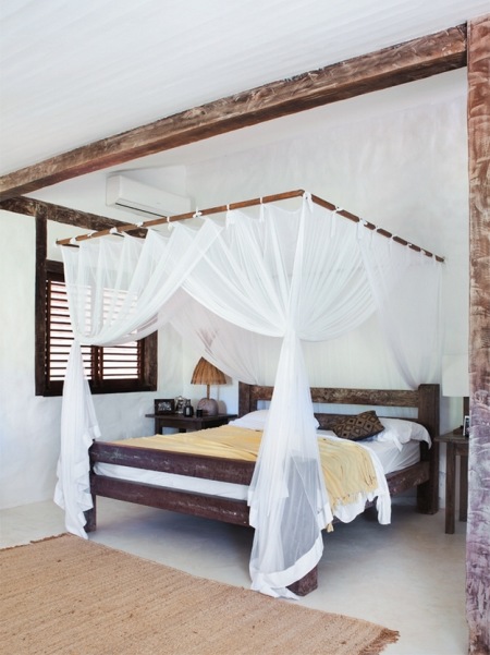 Drewniane łóżko z białymi zasłonami w sypialni