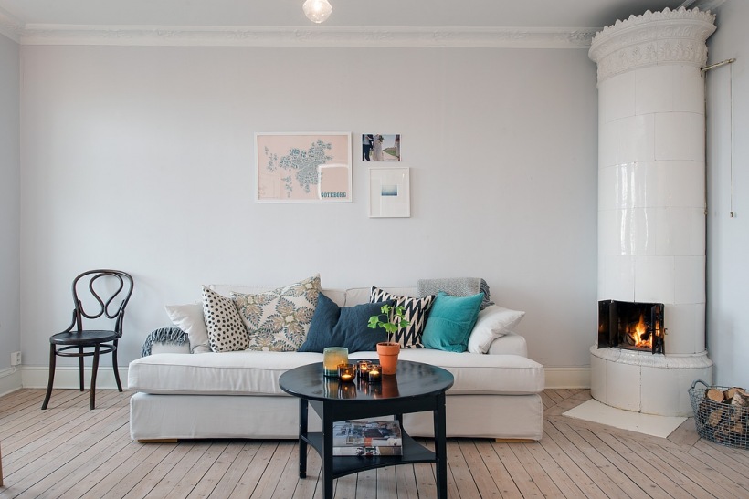 Kolorowe i wzorzyste poduszki na białej sofie w salonie skandynawskim