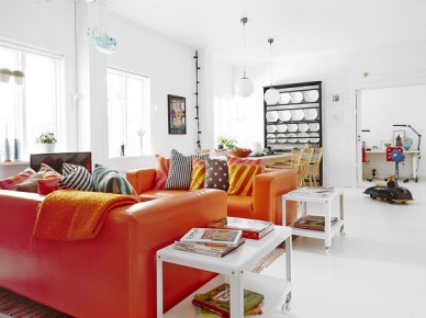Pomarańczowe sofy ze skóry,białe stoliki pomocnicze,czarny regał z pólkami i biała podłoga w salonie (24659)