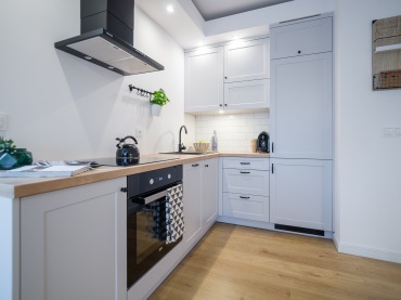 Drewniane blaty w kuchni ładnie komponują się z białymi szafkami i nawiązują do inspiracji stylem skandynawskim. Wnętrze jest dość wysokie, dzięki czemu kuchnia wydaje się większa, niż jest w...