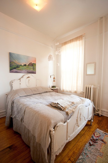 Rzeżbione, białe stylowe łóżko w pastelowej sypialni