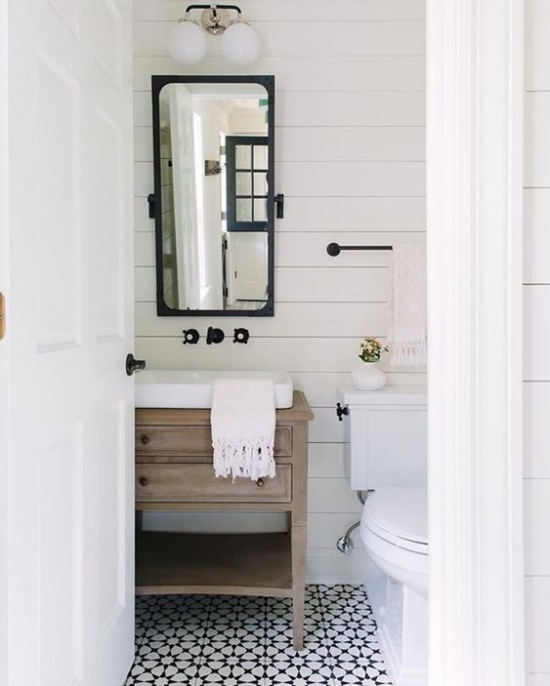 Aranżacja małej łazienki z białym drewnem na ścianie i czarnymi dodatkami