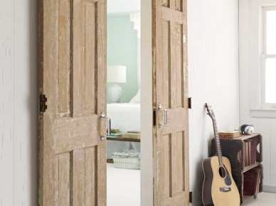 Drewniane drzwi wrota przesuwane na białej ścianie w salonie, sizalowy dywan i szafka niska z drewna (28685)