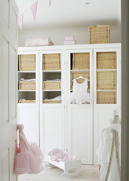 Biała szafa z witrynami i wiklinowymi koszami w dziecięcym pokoju