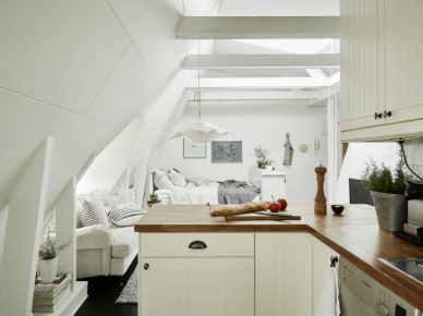 Mała biała kuchnia skandynawska w otwartym widokuz salonem  małego mieszkania na poddaszu (27321)