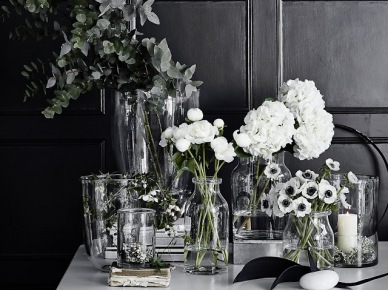 Szklane wazony i butelki z białymi kwiatami do kącika biurowego z czarnymi ścianami (47771)
