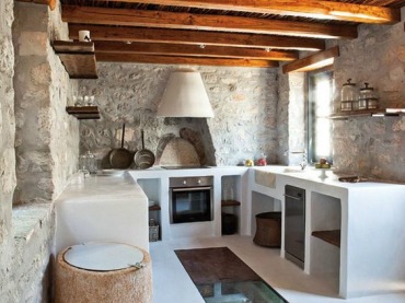 Oryginalna aranżacja kuchni w głównej mierze bazuje na kamieniach, którymi wyłożono ściany. Białe meble i jasna podłoga...