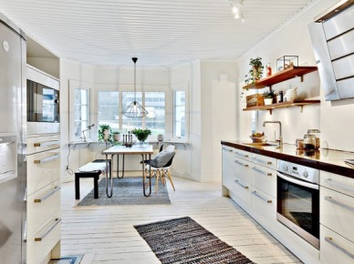 Skandynawska biała kuchnia z czarnymi blatami,bielonymi deskami na podłodze i metalowym stołem z drewnianym blatem (27699)